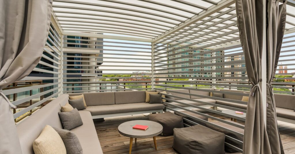 Covered rooftop cabana with cushioned seating and city views, designed as a private outdoor retreat for residents.