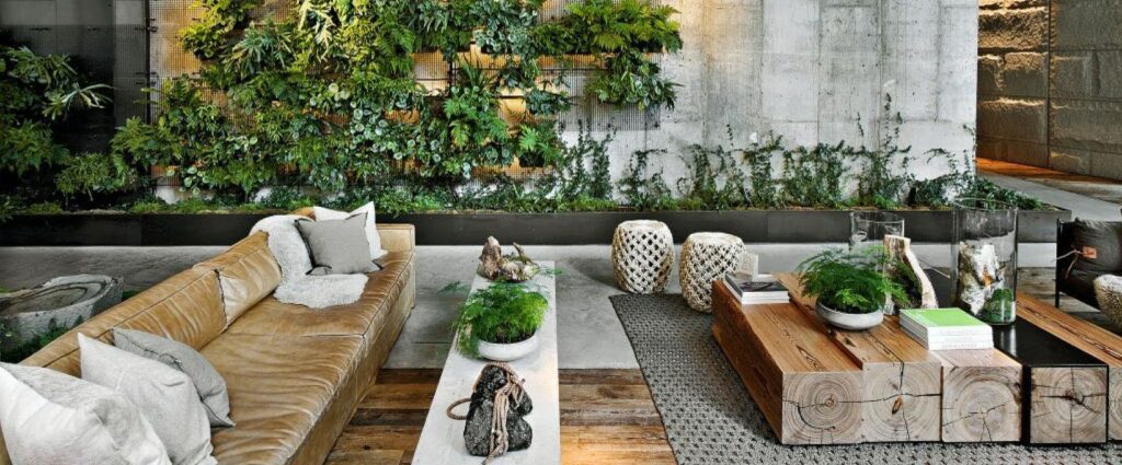 Biophilic lounge with greenery wall, leather sofa and natural wood coffee table in a wellness-focused community space.