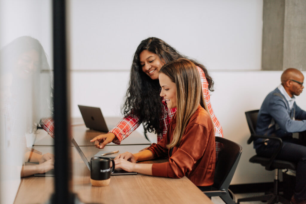 Team members engaging in a collaborative meeting in a meeting room at Kenect Phoenix, with laptops and notebooks on the table.